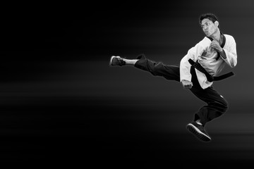 Fototapeta na wymiar Taekwondo man jump flying high kick on black for poster background with clipping path