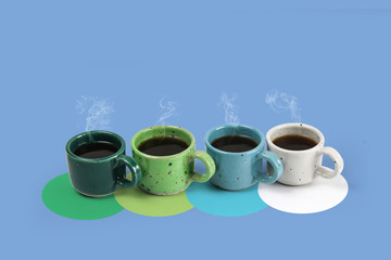 Four colorful cups with fresh coffee on colors background, colors green, blue and white