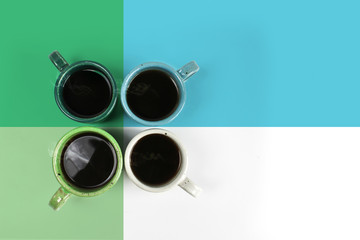 Four colorful cups with fresh coffee on colors background, colors green, blue and white