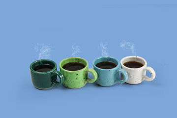 Four colorful cups with fresh coffee on colors background, colors green, blue and white