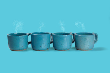 Four blue cups with fresh coffee on blue background.