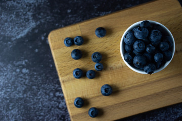 Raw blueberry in a white bowl on dark background.