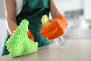 Worker in gloves cleaning table with rag, closeup. Space for text