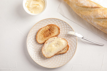 Tasty bread with butter served for breakfast on white table, top view
