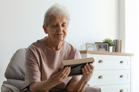 Elderly woman with framed photo at home