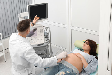 Young pregnant woman undergoing ultrasound scan in modern clinic