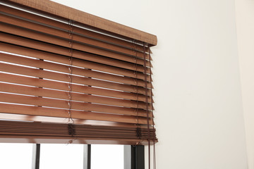 Modern window with stylish wooden blinds indoors. Space for text