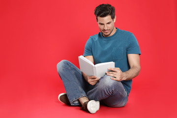 Handsome man reading book on color background, space for text