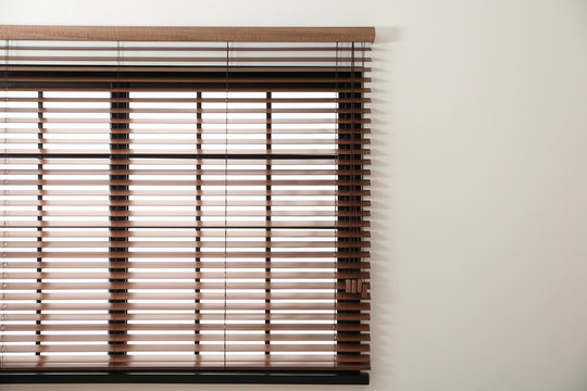 Modern window with stylish wooden blinds indoors. Space for text