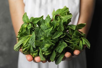 Young woman holding bunch of fresh mint, closeup - Powered by Adobe