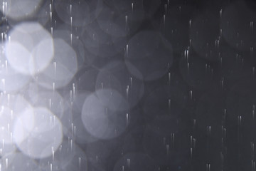 Rain drops falling down against dark background
