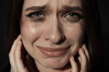 Crying young woman on dark background. Stop violence