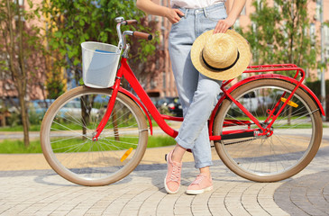Young woman near modern color bicycle outside, closeup