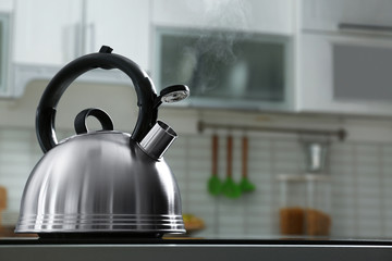 Modern kettle with whistle on stove in kitchen, space for text