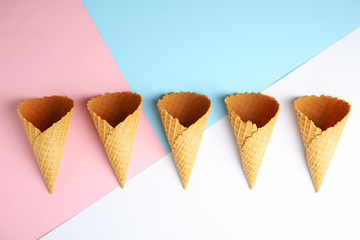 Empty wafer ice cream cones on color background, flat lay