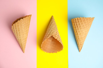 Empty wafer ice cream cones on color background, flat lay