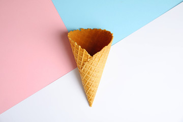 Empty wafer ice cream cone on color background, top view