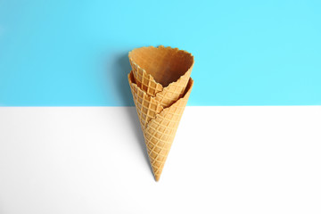 Empty wafer ice cream cones on color background, flat lay