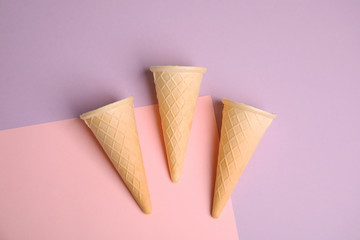 Empty wafer ice cream cones on color background, flat lay