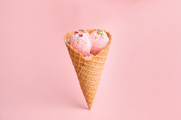 Delicious ice cream in wafer cone on pink background