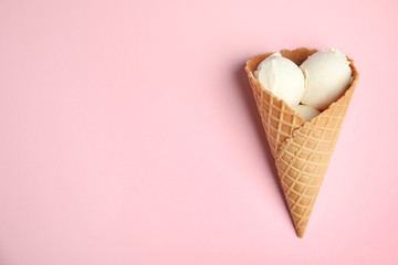 Delicious vanilla ice cream in wafer cone on pink background, top view. Space for text