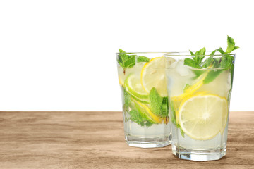 Glasses of refreshing drink with citrus slices and mint on wooden table against white background