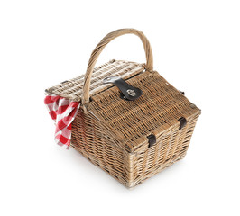 Closed wicker picnic basket with checkered blanket on white background