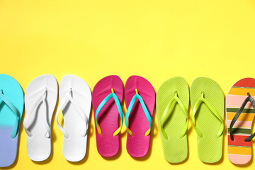 Different flip flops and space for text on yellow background, flat lay. Summer beach accessories