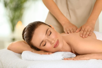 Fototapeta na wymiar Beautiful young woman enjoying massage in spa salon