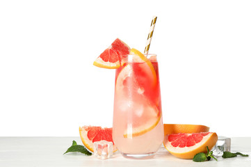 Glass of grapefruit refreshing drink with ice cubes and straw on wooden table against white background