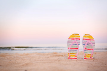 Obraz premium Stylish flip flops on sand near sea, space for text. Beach accessories