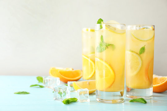 Glasses of citrus refreshing drink on light blue wooden table, space for text