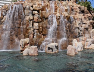 Medium wide shot of water cascading down a man-made waterfalls in a landscaped garden