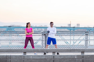 Couple exercise on the bridge at the end of day with headphones on head