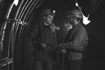 Two young guys in special clothes and helmets standing in the mine. Miners