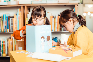 Dark-haired girls in bright shirts being busy with learning materials