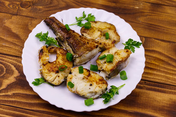 Roasted pollock in white plate on a wooden table