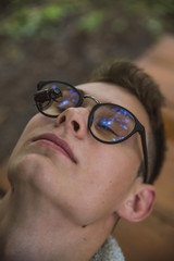 a young rebel in a jacket and jeans on the background of an old crumbling building with glasses and...