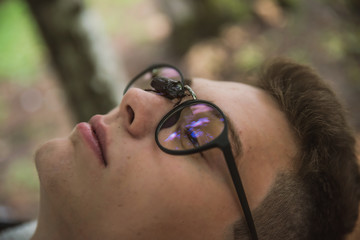 a young rebel in a jacket and jeans on the background of an old crumbling building with glasses and...