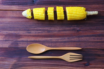 pieces of corn instant cooking with wooden spoon and fork on brown wood table