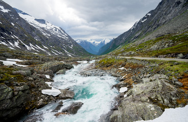 Fototapeta na wymiar Norwegian landscape with mountains, streaming rivers and waterfalls. 100-year-old national tourist route (The Old Stryn Mountain Road), country road 258, close to summer ski center.