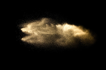 Abstract sand cloud.Golden colored sand splash agianst dark background.Yellow sand fly wave in the...