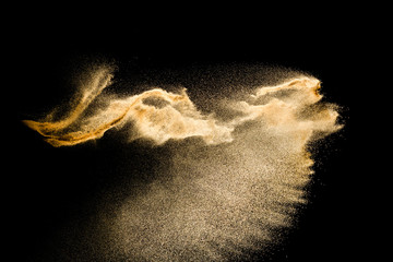 Naklejka na ściany i meble Abstract sand cloud.Golden colored sand splash agianst dark background.Yellow sand fly wave in the air. Sand explode on black background ,throwing freeze stop motion concept.