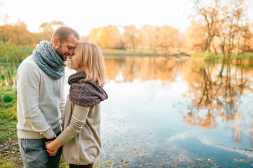 Loving couple in knitted clothes romantic portrait with reflected lake on background.