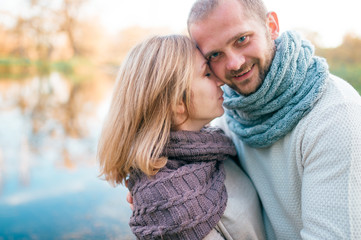 Fototapeta premium Loving couple in knitted clothes romantic portrait with reflected lake on background.
