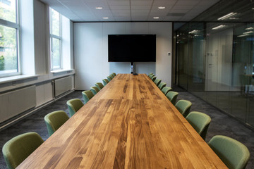 Coronavirus office closed work from home. Meeting room or Board room with empty presentation LCD screen at the head of the table in modern office.