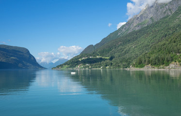 Naklejka na ściany i meble Panoramic view of The Sognefjord (Sognefjorden), nicknamed the King of the Fjords. Te largest and deepest fjord in Norway. Symmetry created by reflections in the still ocean water. Bright midsummer.