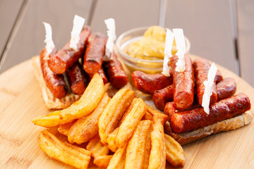 Spicy sausages on toast bread with fried potato on wooden plate , wood background.