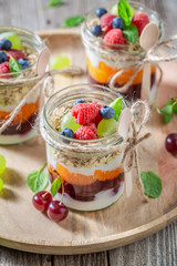 Healthy granola with fresh berries and yoghurt in jar