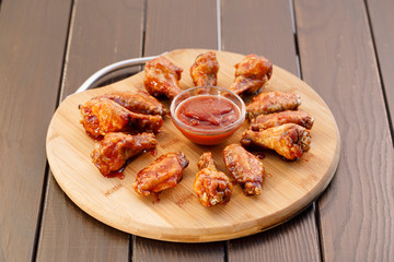 Spicy deep fried chicken wings and legs with dipping sauce on wooden plate , wood background.